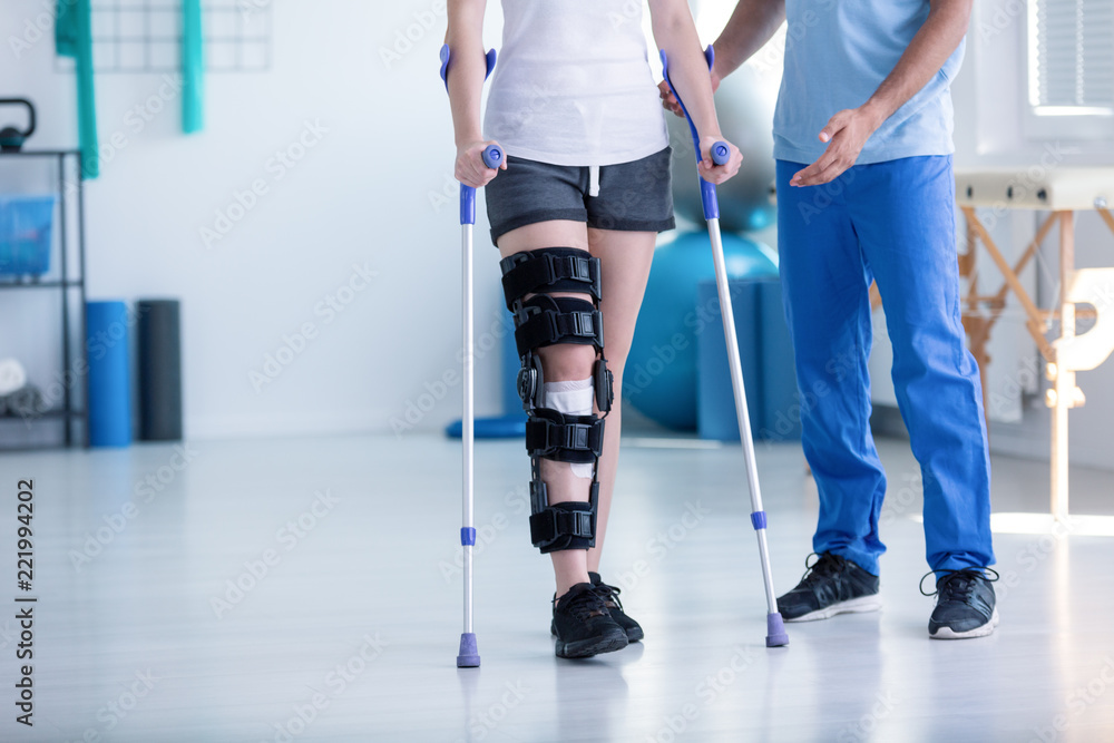 运动理疗师和拄着拐杖训练时腿部受伤的患者