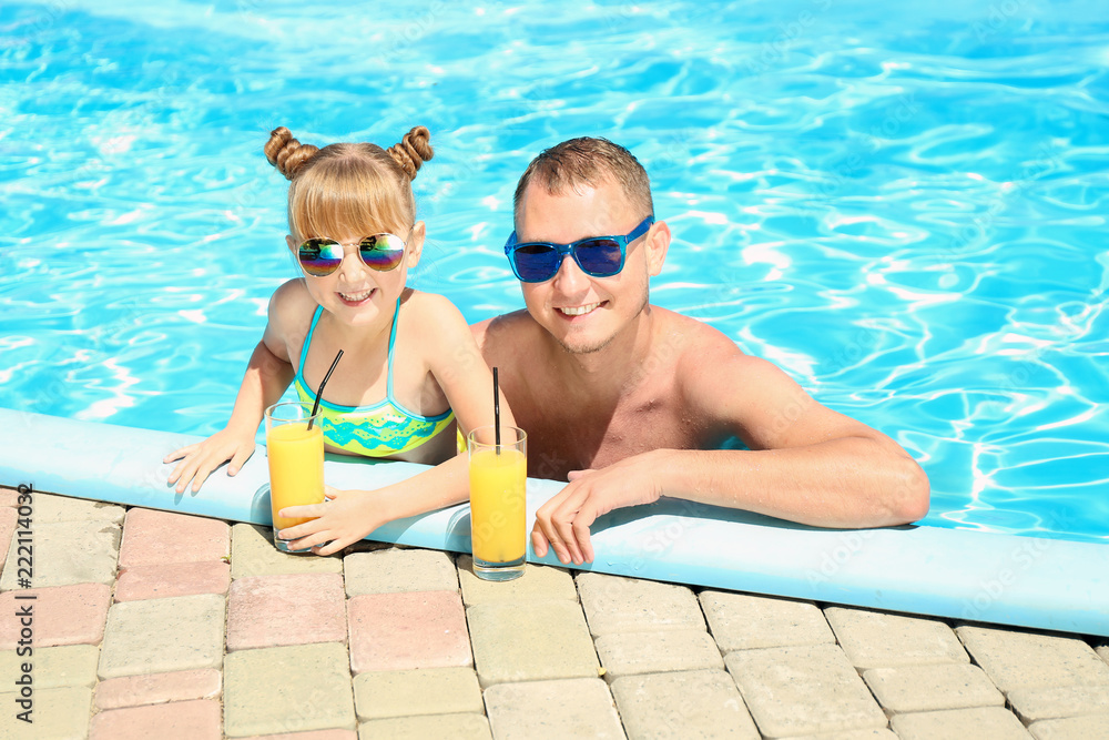 快乐的父女俩在游泳池里喝着果汁休息