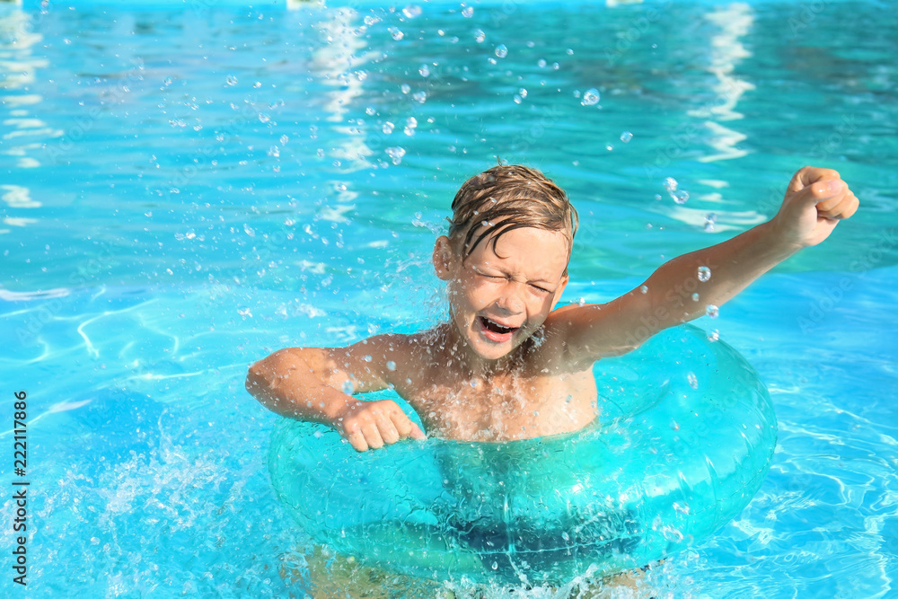 夏天，可爱的小男孩带着充气环在游泳池游泳