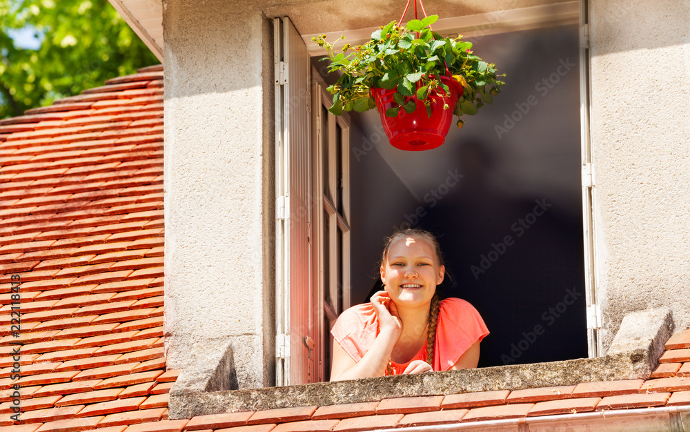 快乐的女孩从阁楼的窗户望向外面的街道