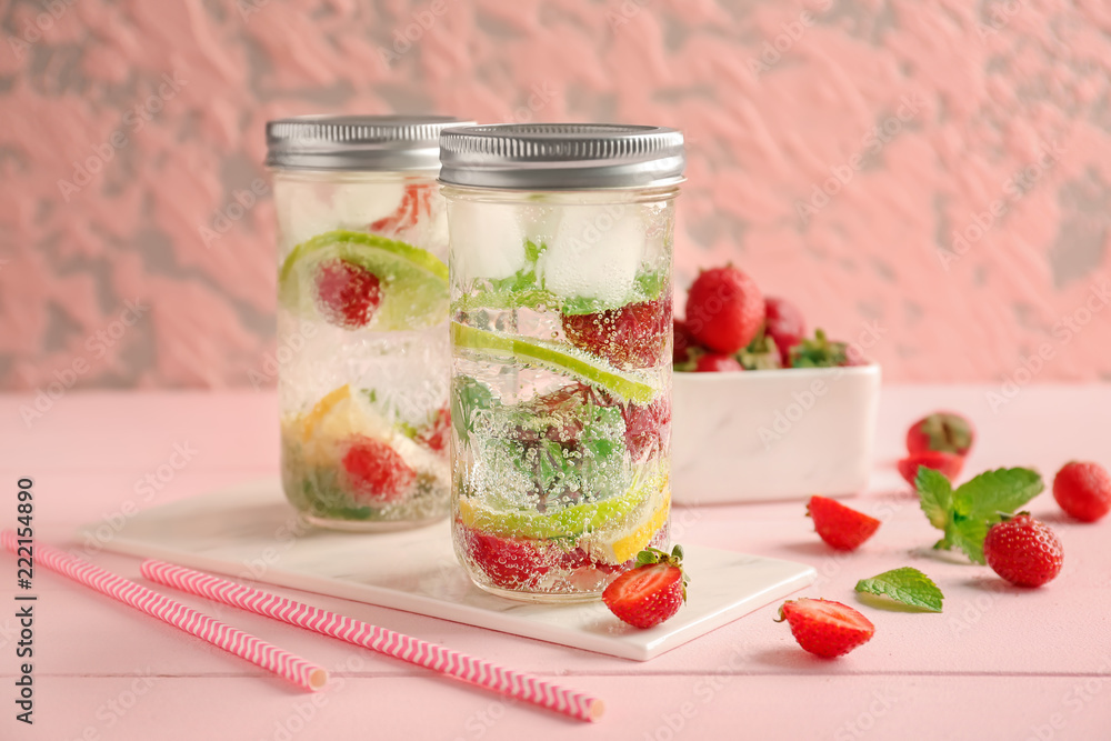 Jars of fresh strawberry lemonade on color wooden table