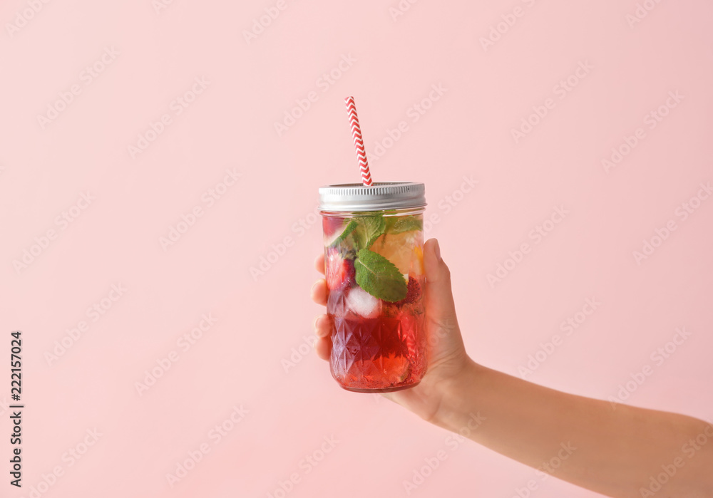 拿着一罐彩色背景的新鲜草莓柠檬水的女人