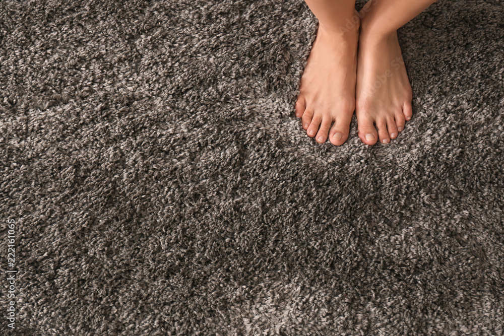 赤脚女人站在蓬松地毯上的腿