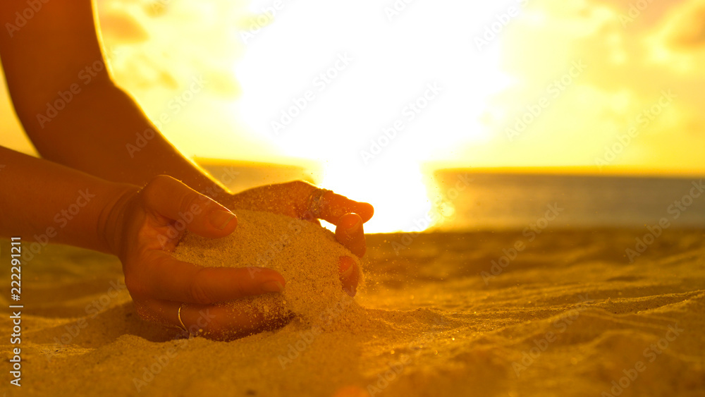 特写：无法辨认的女游客在美丽的日落下撒沙子