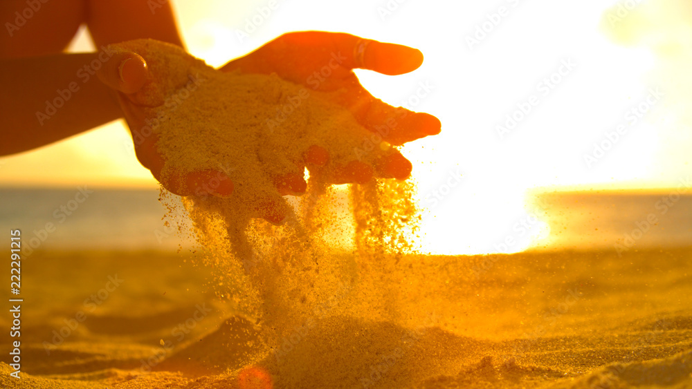 特写：无法辨认的女性游客在日落时与温暖的沙子玩耍。
