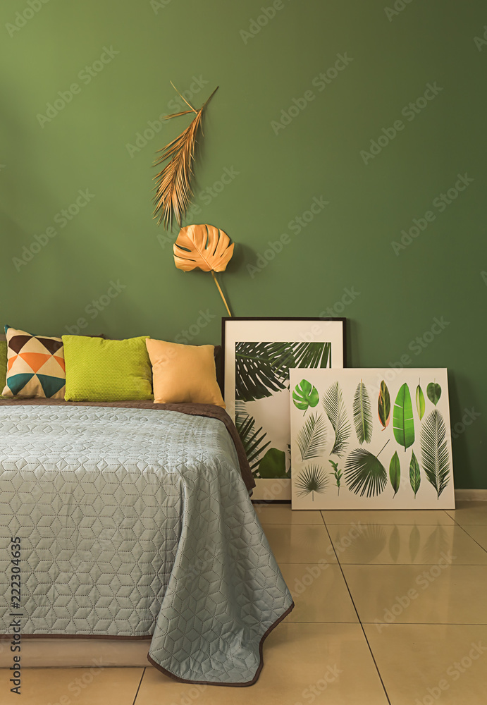 彩色墙上金色热带树叶的现代舒适卧室内部