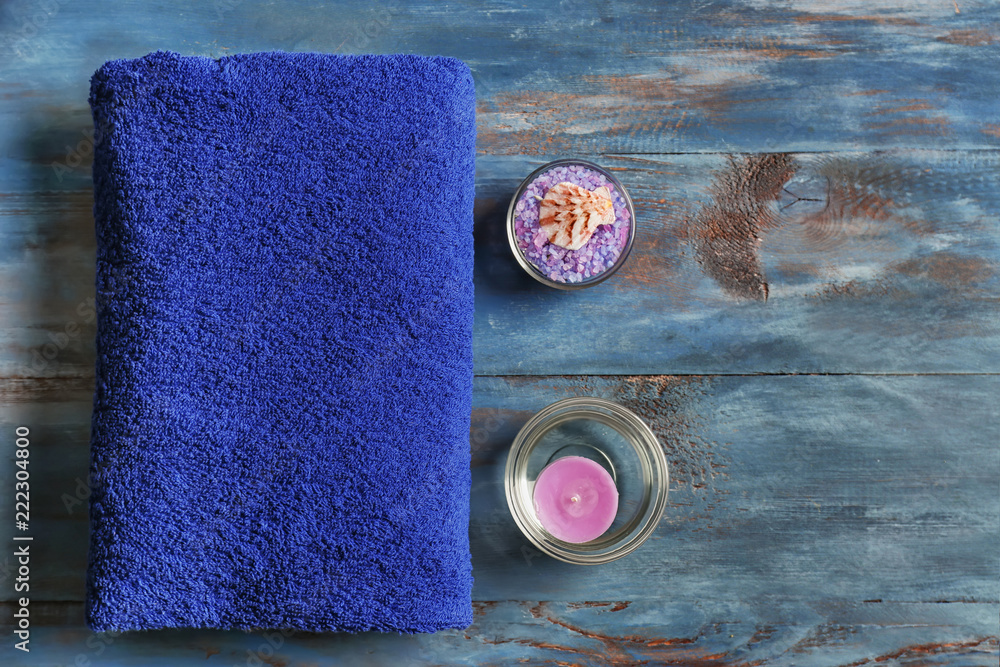 Soft towel with aromatic candle and sea salt on color background