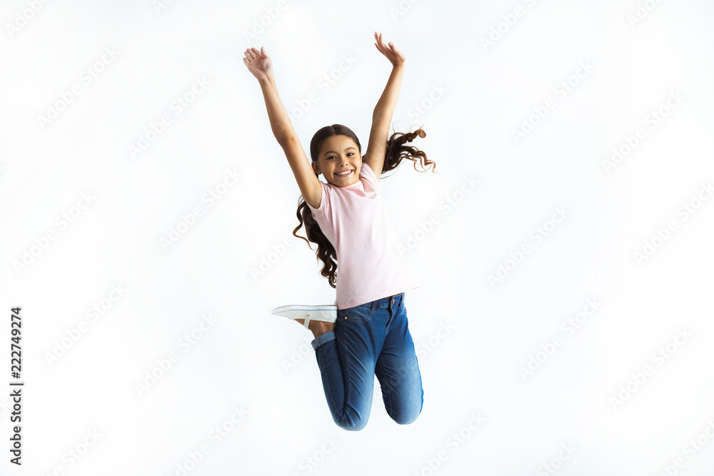 在白墙背景上跳跃的快乐女孩
