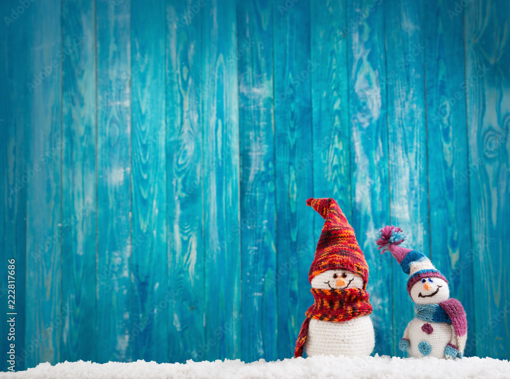蓝色背景下柔软雪地上的小针织雪人