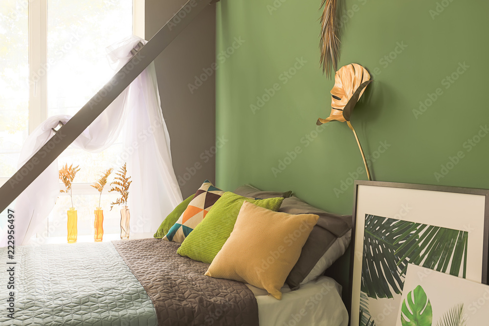彩色墙上有金色热带树叶的现代舒适卧室内部