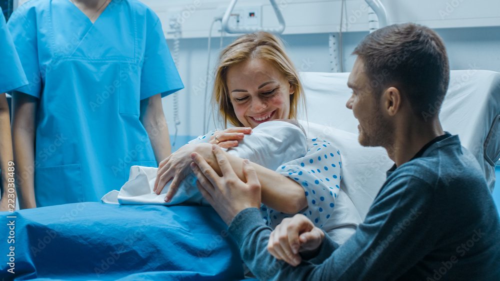在医院里，母亲抱着新生儿，父亲慈爱地拥抱着婴儿和妻子。幸福的Fa