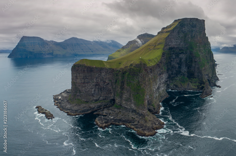 空中飞行：在一个长满草的小岛上飞行，岛上有高耸的黑色岩石悬崖。