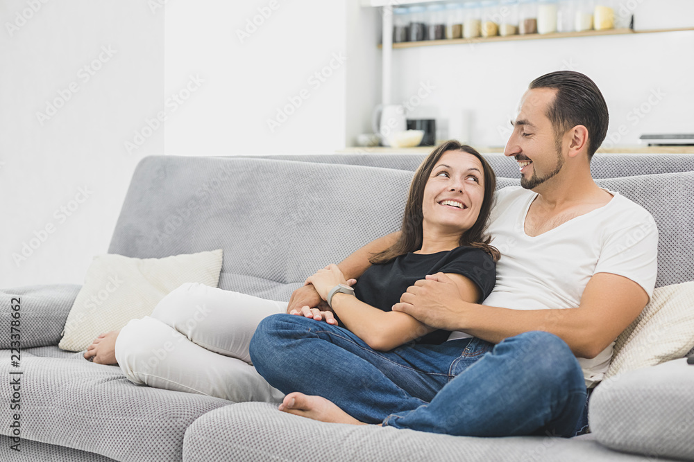 坐在新沙发上的情侣正在互相注视。现代公寓。舒适的新概念