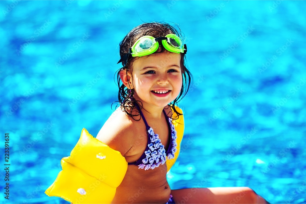 美丽的小女孩在泳池边晒太阳