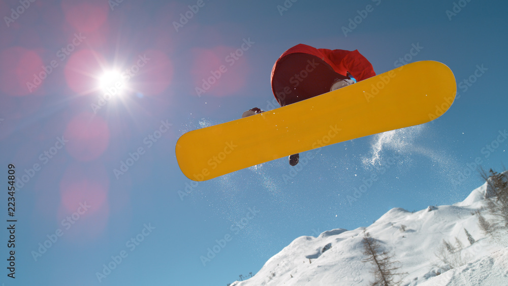 特写：单板滑雪运动员在晴朗的蓝天上跳过太阳