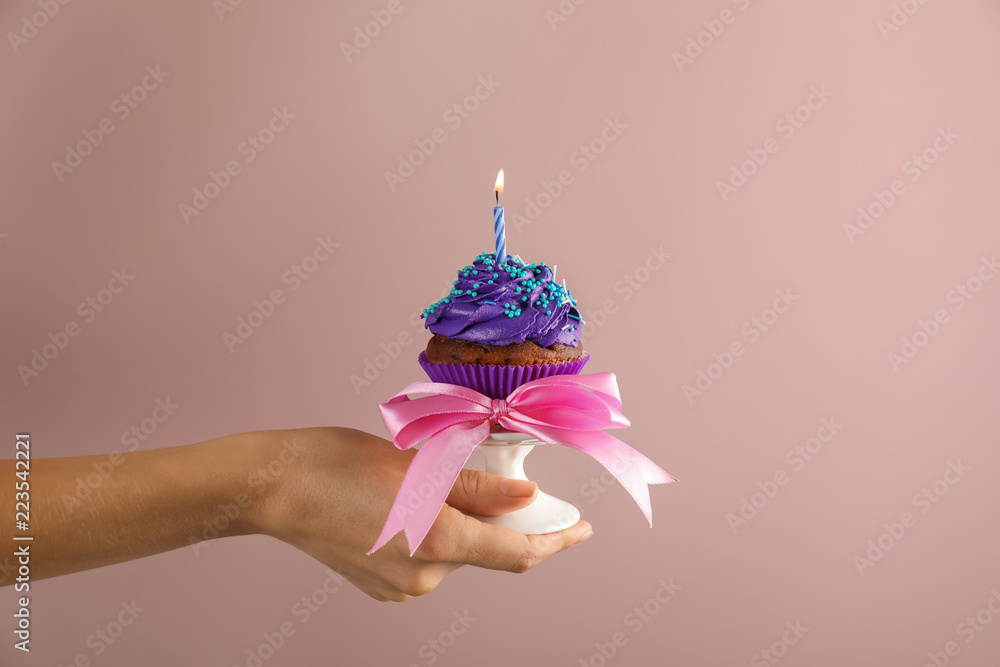 女人拿着彩色背景蜡烛的生日纸杯蛋糕