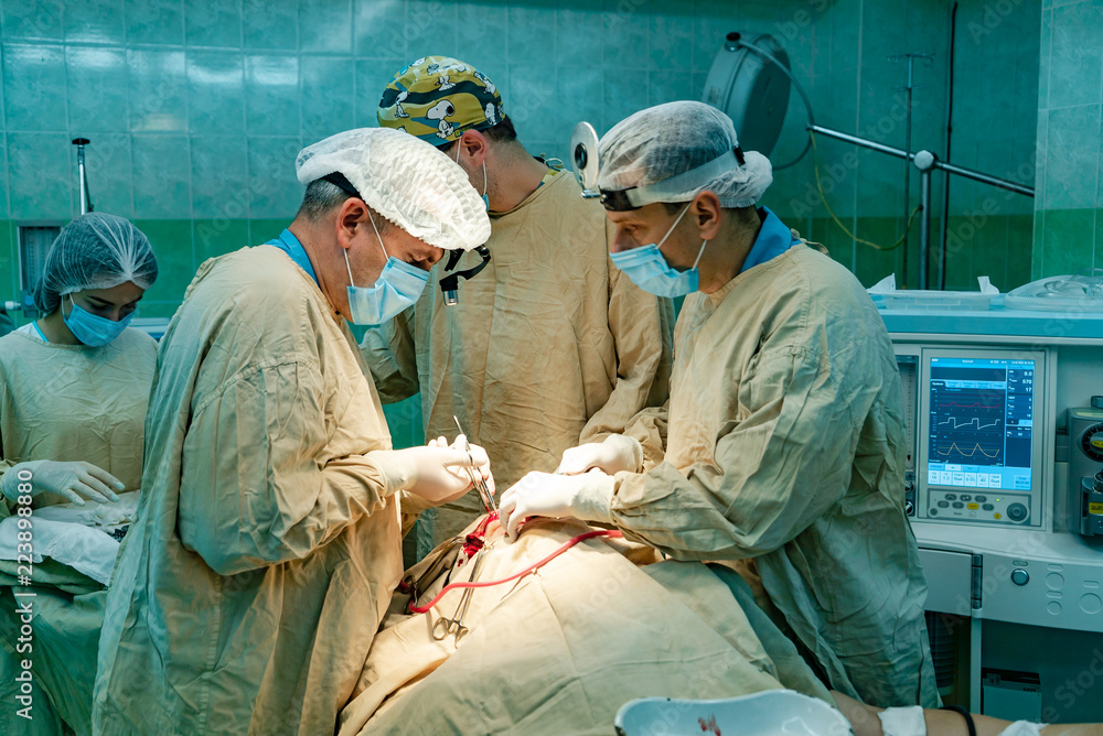 手术过程中，三名医生和一名护士站在一名男子的脸旁。医生追踪