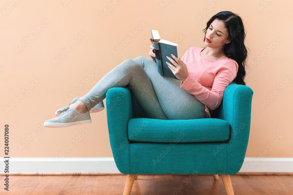 椅子上拿着书的年轻女人