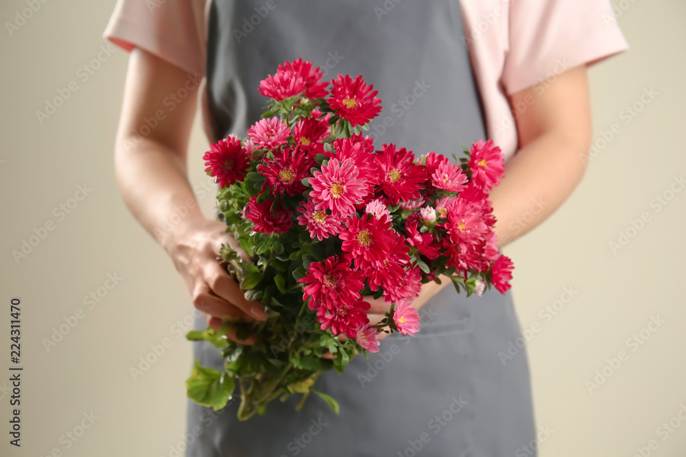女花艺师手持一束美丽的菊花，背景为浅色
