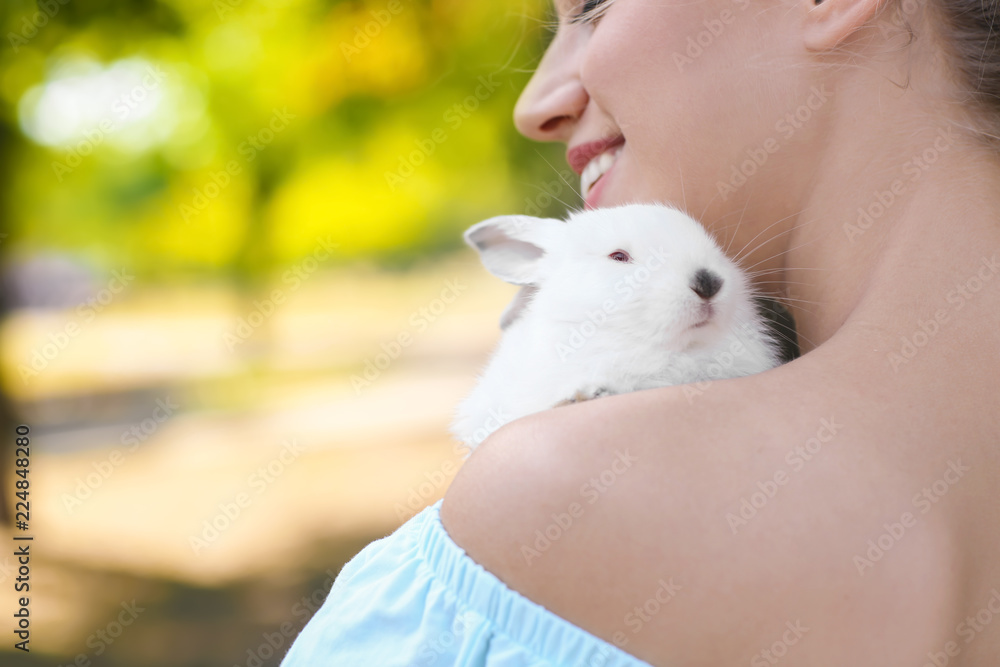 美丽的年轻女子在户外带着可爱的兔子