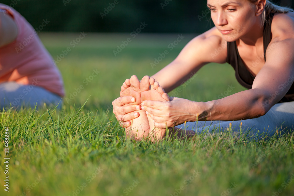 公园里的瑜伽，中年妇女近距离伸展双脚