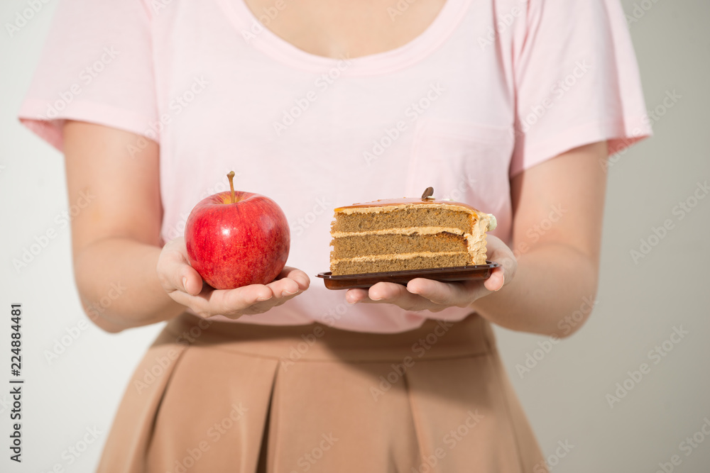 女孩一手拿着苹果，另一手拿蛋糕。