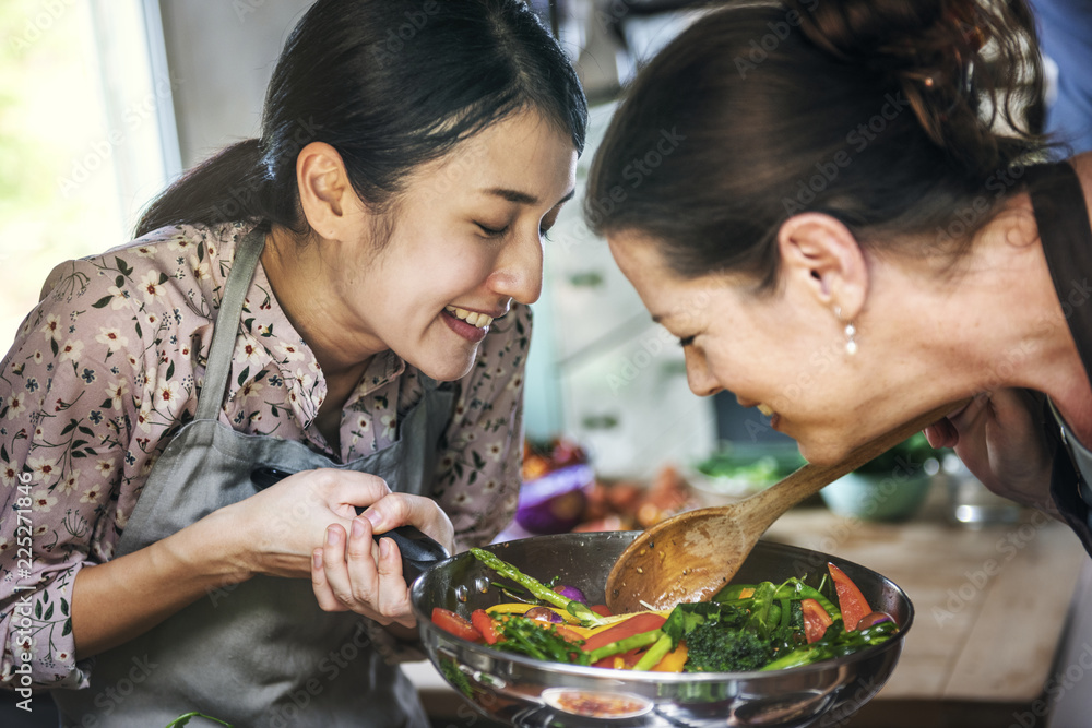 Two women cooking healthy vegetables in a pan