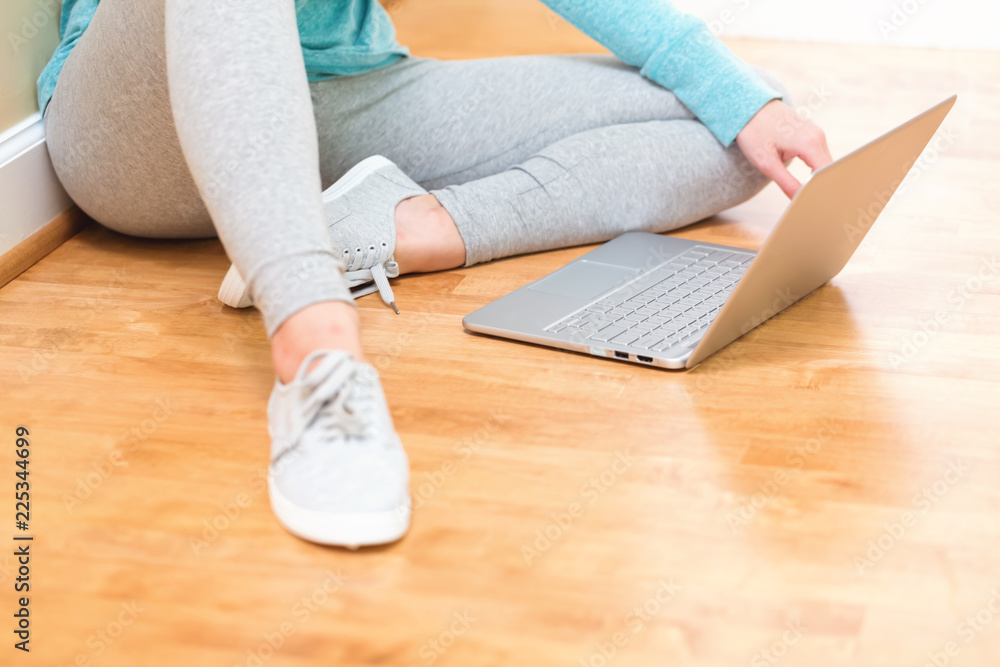 年轻女子在地板上使用笔记本电脑