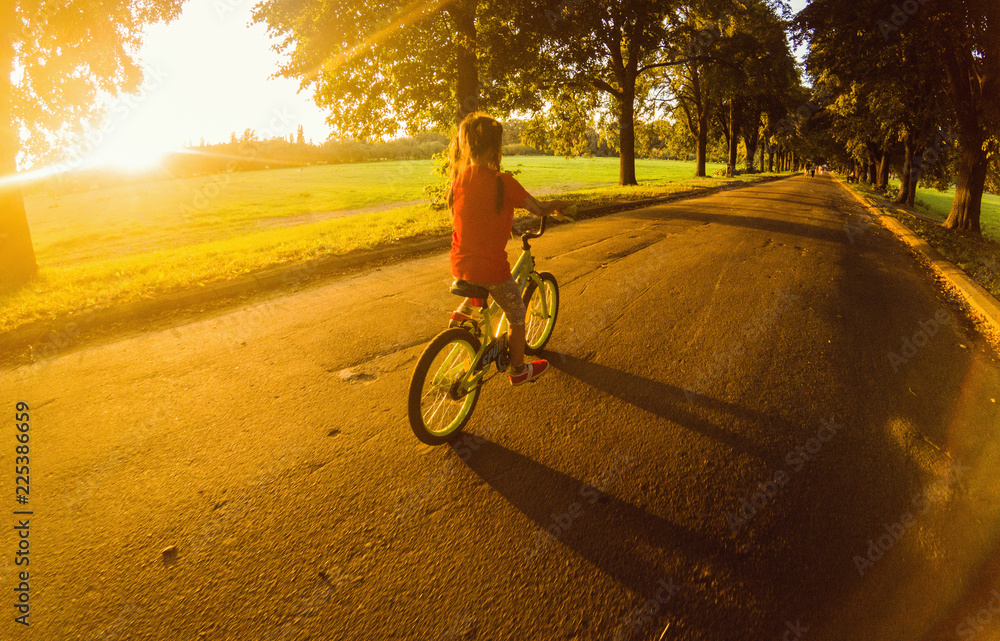日落时骑自行车的小女孩