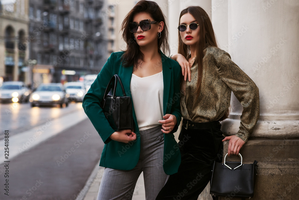 户外时尚写真，两位年轻美女戴着时髦的太阳镜，穿着时髦的衣服，ho