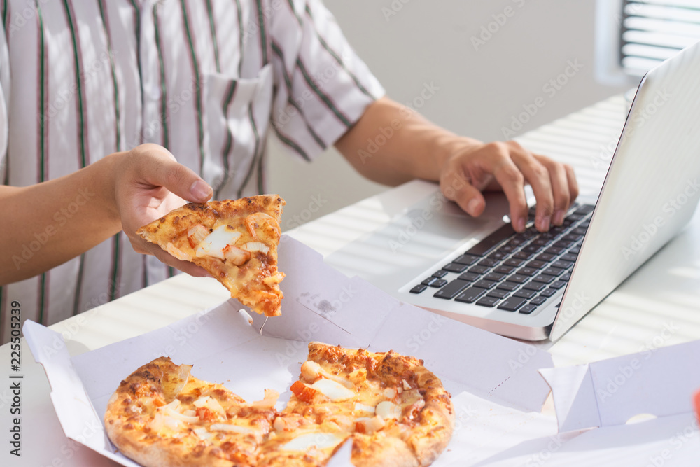 Eating pizza and social networking with a laptop.