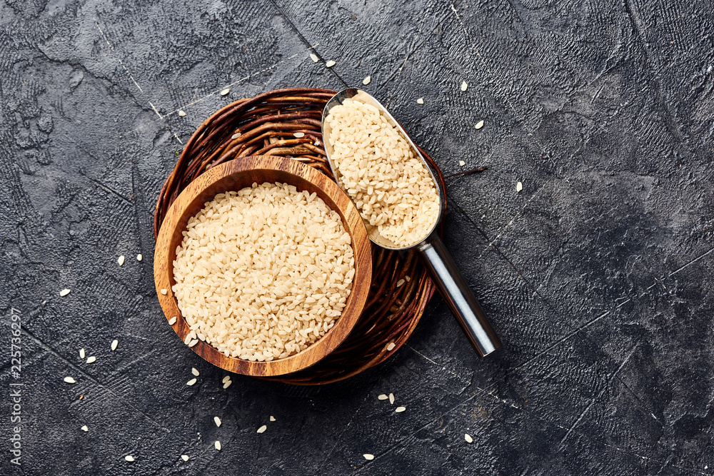 黑色背景的木制碗中的白米饭。谷物俯视图。