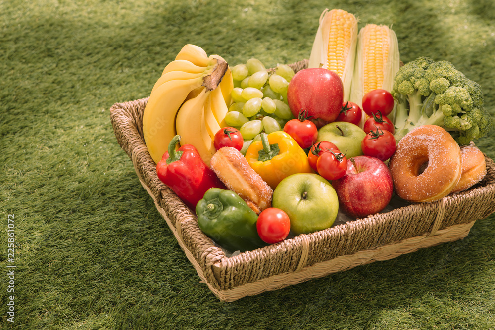 草地上野餐毯上的新鲜健康热带水果，配葡萄、苹果、葡萄柚、橙子