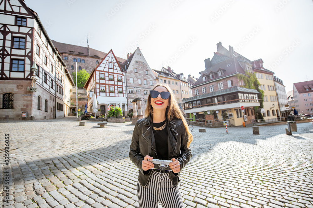 一位年轻的女游客站在美丽的城市广场上的画像，广场上有古老的建筑，travelin