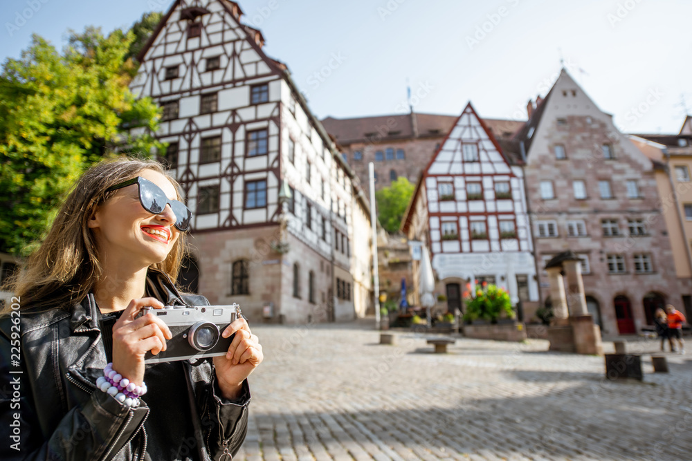 一位年轻的女游客站在有着古老建筑的美丽城市广场上的肖像，travelin