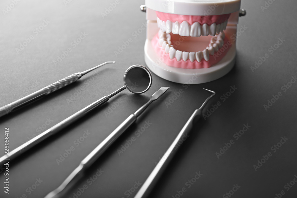Dentists tools with artificial jaw on dark table