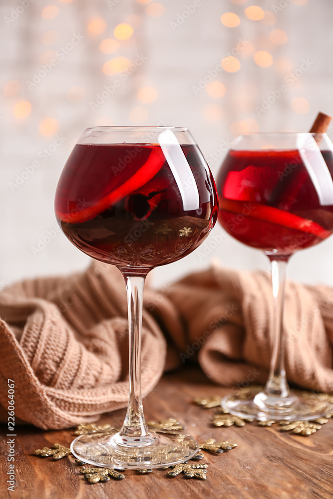 Glasses of delicious mulled wine with warm plaid on wooden table