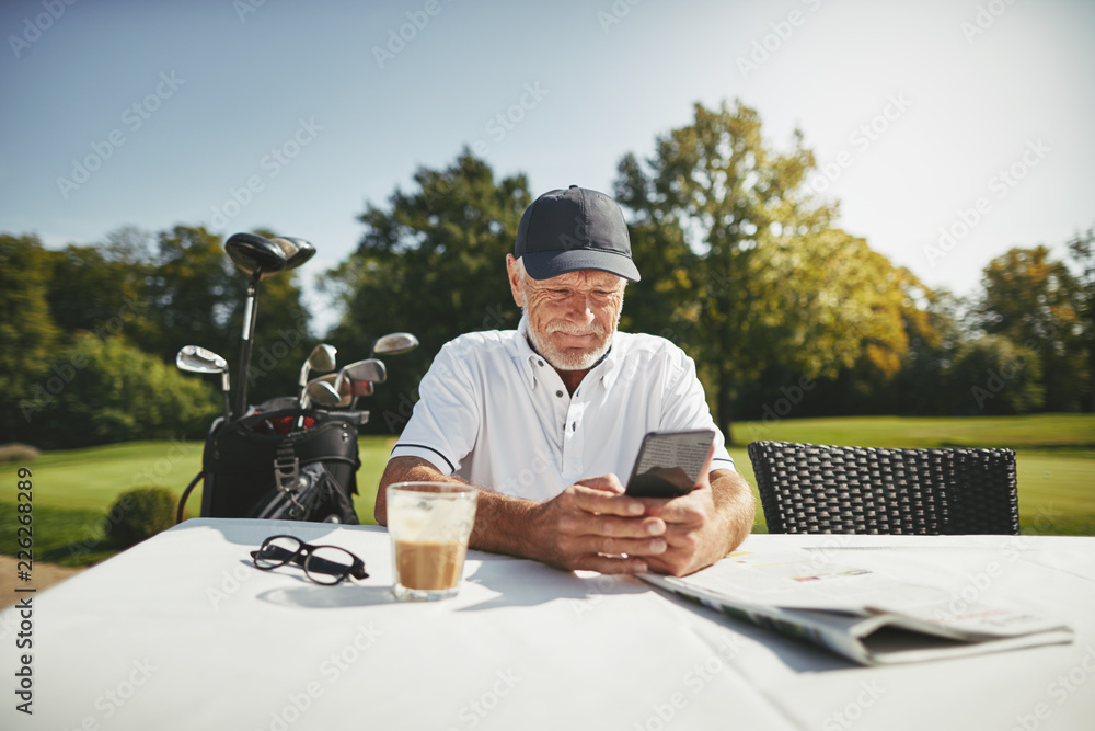 一名老年男子在高尔夫俱乐部餐厅使用手机