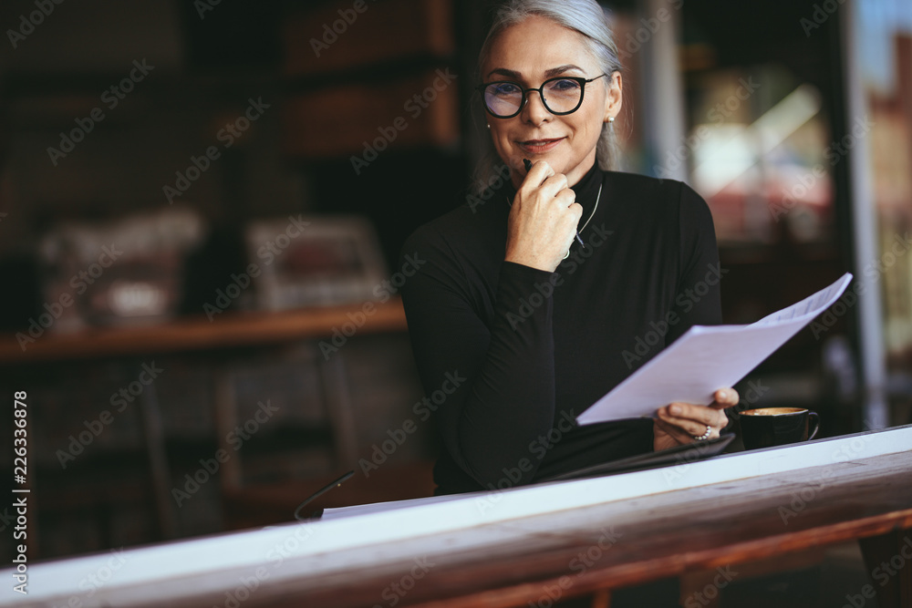 坐在咖啡店工作的老妇人