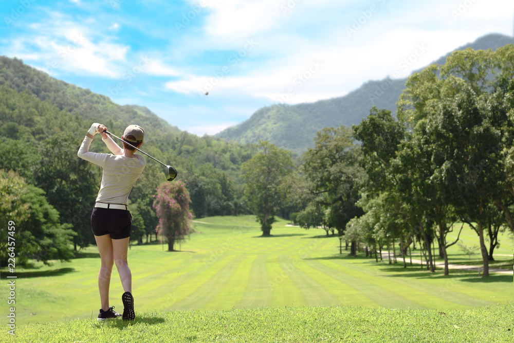 亚洲年轻女子在美丽的天然高尔夫球场上打高尔夫
