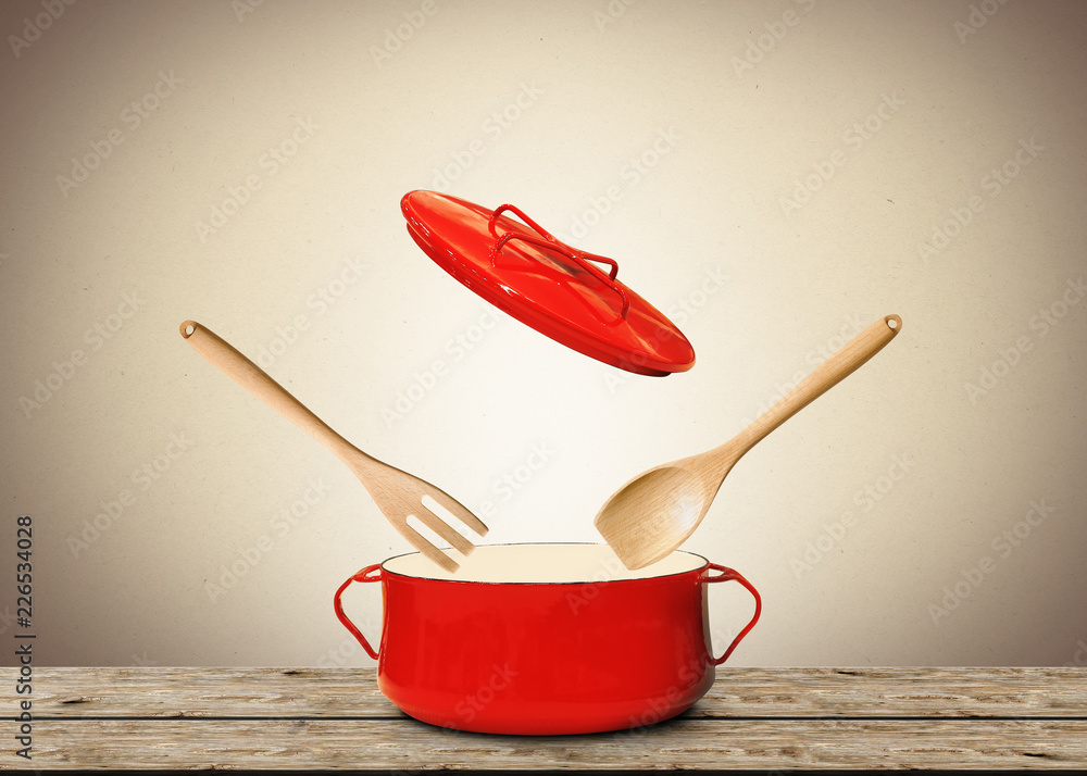 用叉子和勺子盛汤的大红锅