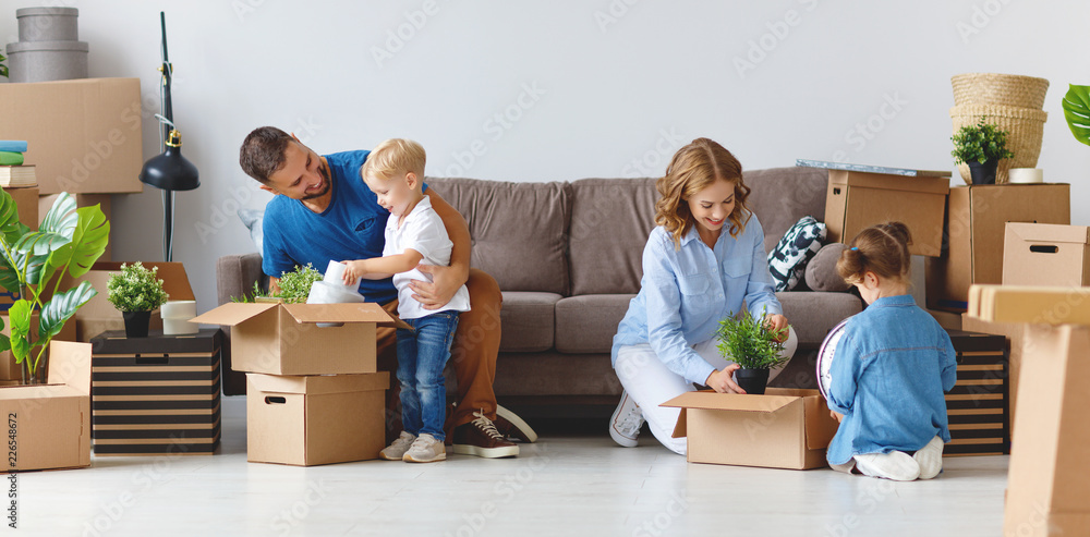 幸福家庭的母亲、父亲和孩子搬到新公寓并打开箱子