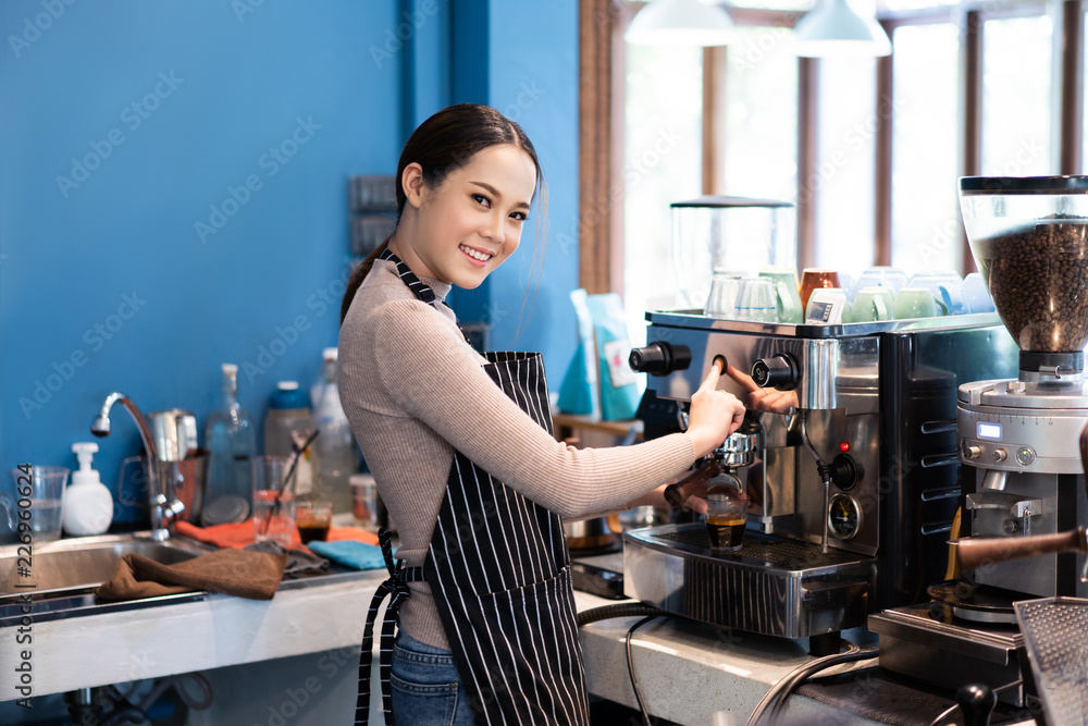一位亚洲女咖啡师正在一家企业经营的商店里煮咖啡。