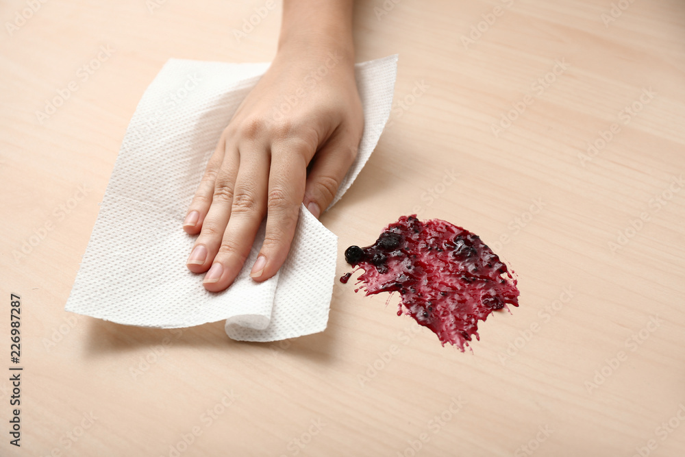 妇女用纸巾擦拭木桌上的果酱点