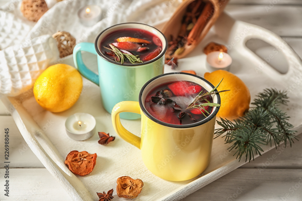 Metal cups of delicious mulled wine on white tray