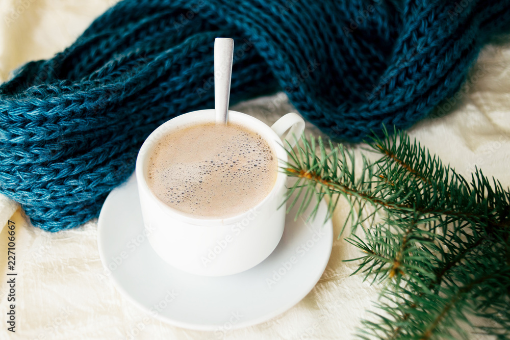 一杯牛奶茶，织物背景，针织毛衣和针。