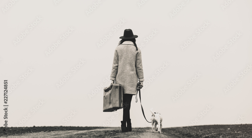 带着行李箱和狗站在路上的年轻美女。黑白色猪圈图片