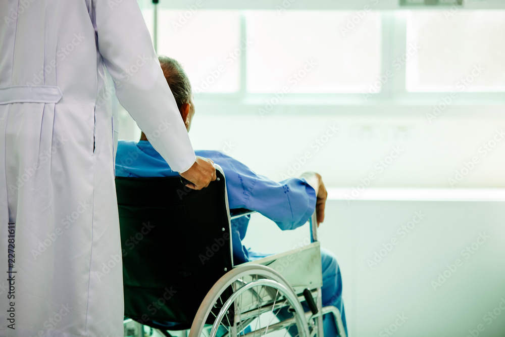 坐在轮椅上的亚洲患者与亚洲医生坐在医院里。