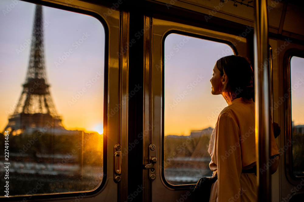 巴黎日出时，年轻女子坐地铁欣赏埃菲尔铁塔