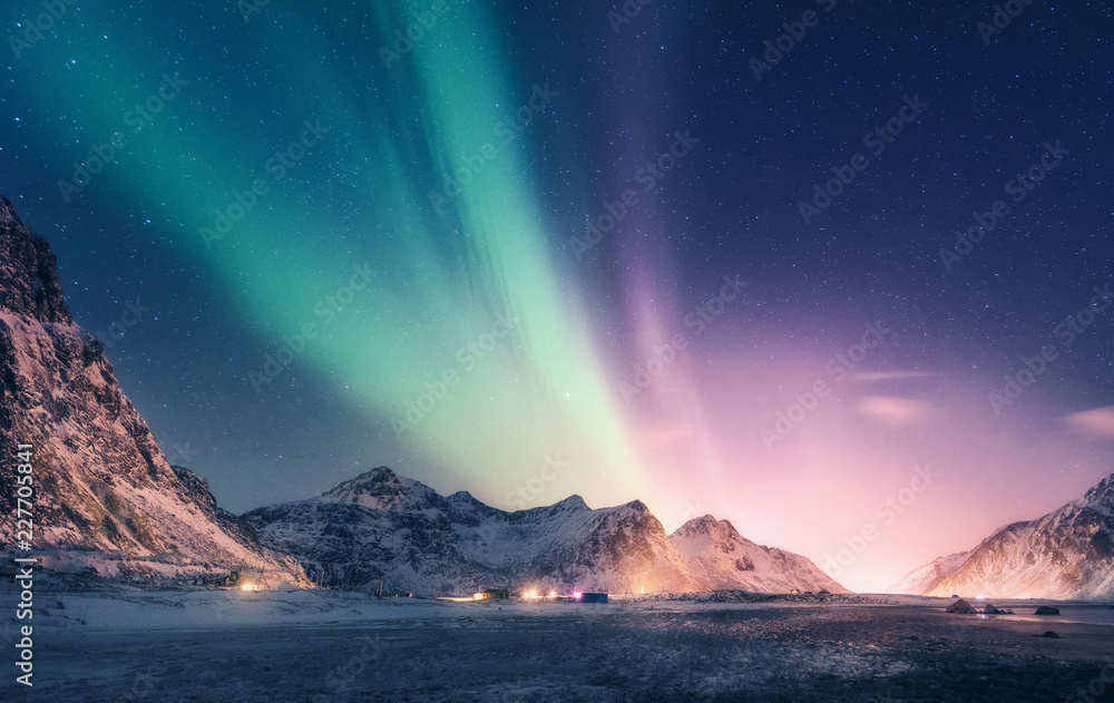 雪山上的绿色和紫色北极光。挪威罗弗敦群岛的北极光。S